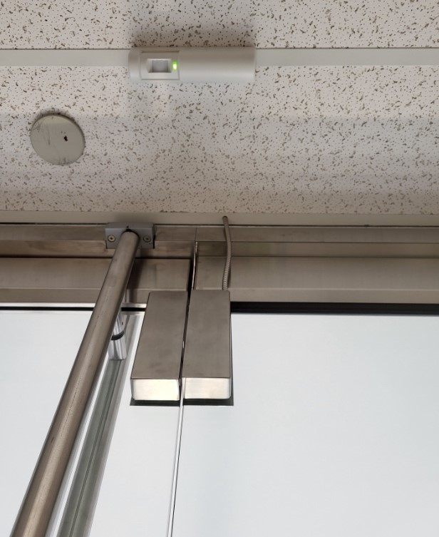 Entrance door for a function center with self-detecting release sensor in the ceiling