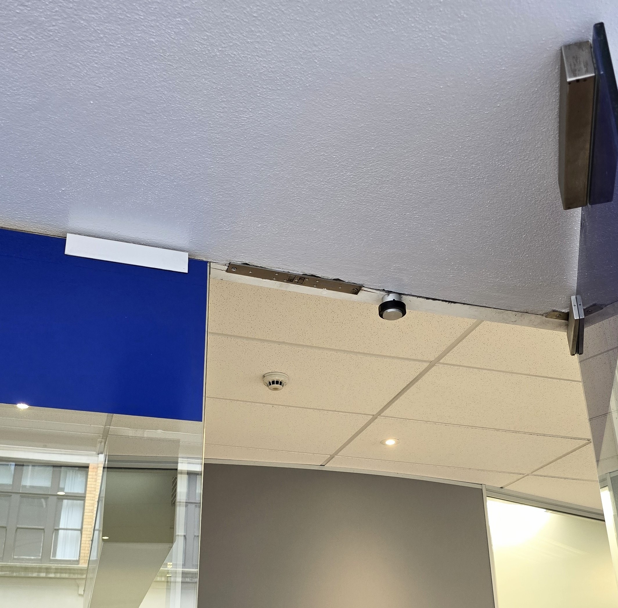 Glass door with surface mounted strike housing and lock morticed into the header